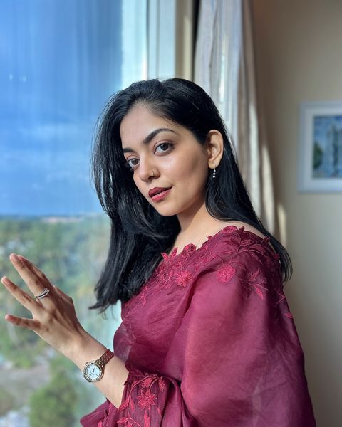 Ahaana Krishna in a maroon saree, three-quarter portrait by a window