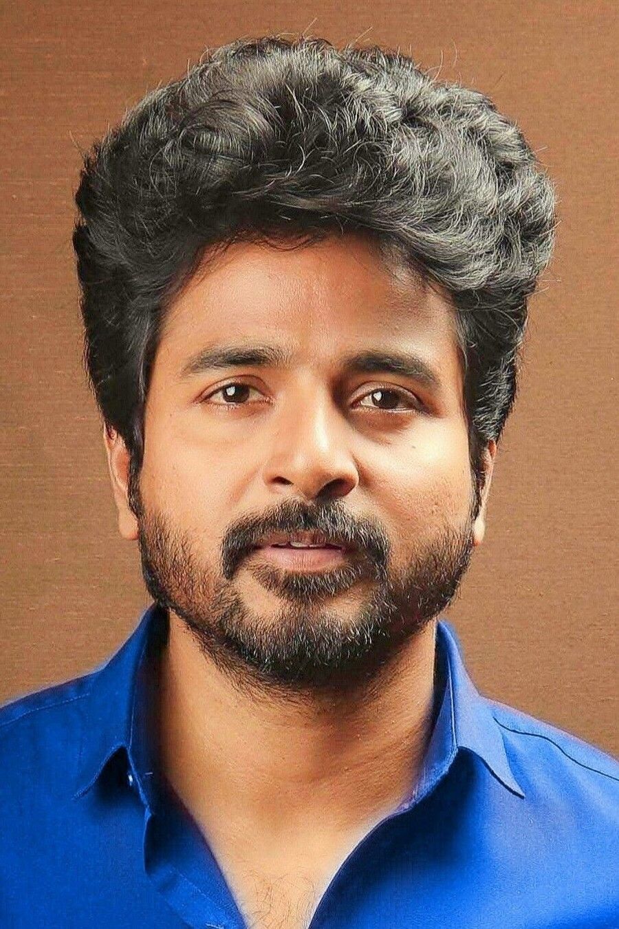 Sivakarthikeyan with a beard in a bright blue shirt, portrait