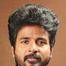 Sivakarthikeyan with a beard in a bright blue shirt, portrait