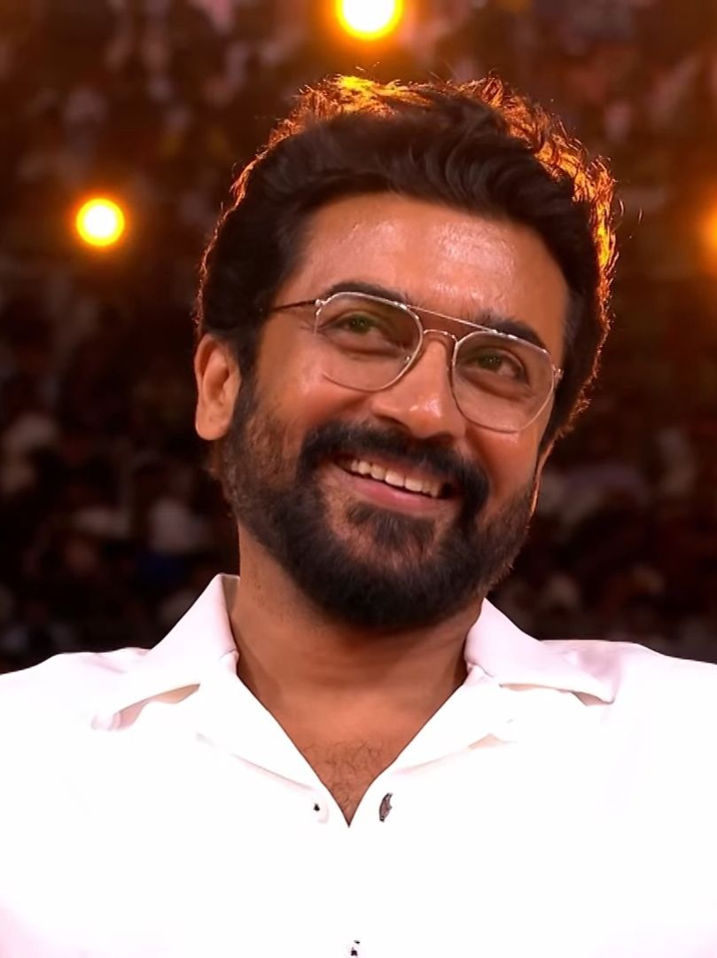 Suriya smiling in glasses and a white shirt at the Retro audio launch