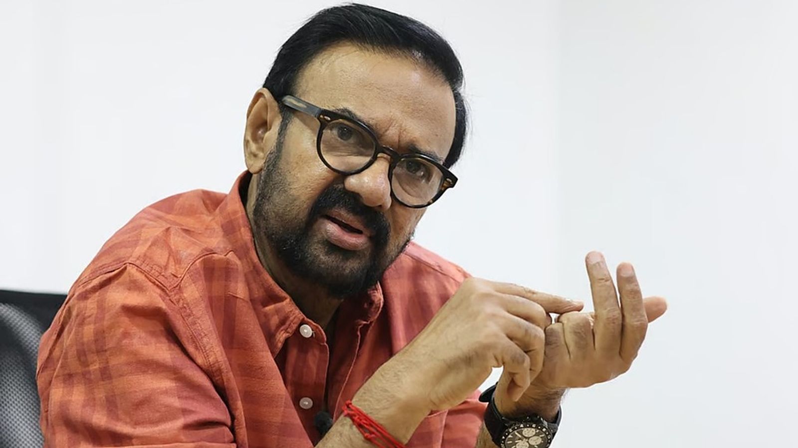 Actor Maniyanpilla Raju in glasses and an orange checked shirt, speaking