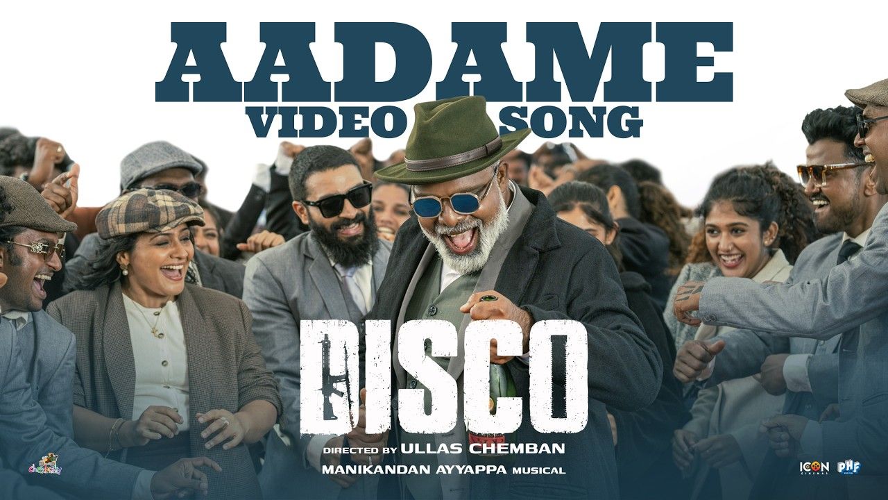 Disco Aadame song still with a grey-bearded man in a green hat and blue glasses dancing among a cheering crowd in suits