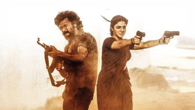 DC still of a man and a woman firing guns in a dusty open field