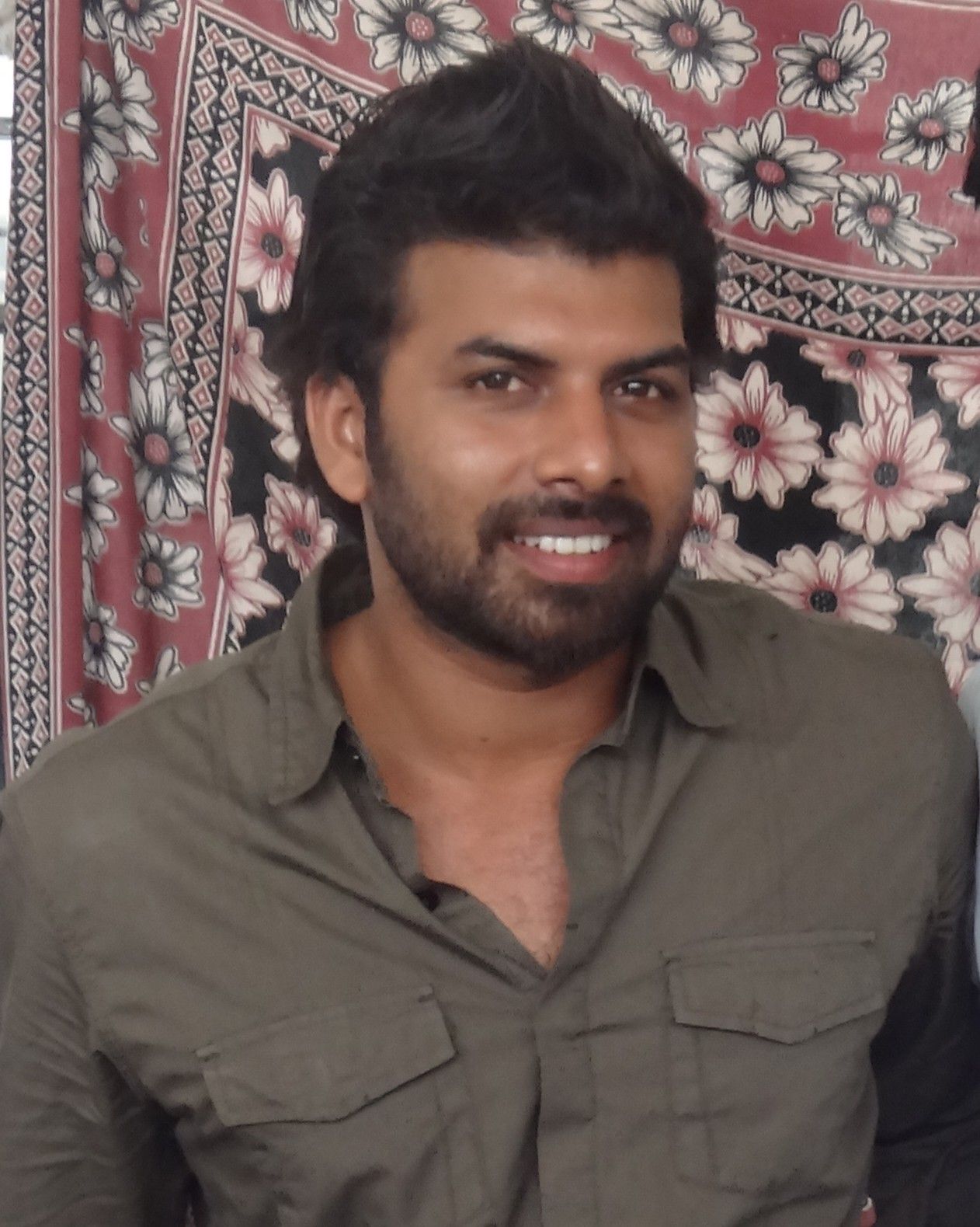 Sunny Wayne with a beard in a grey shirt, indoor portrait