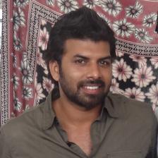 Sunny Wayne with a beard in a grey shirt, indoor portrait