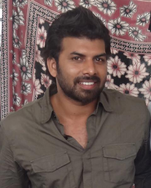 Sunny Wayne with a beard in a grey shirt, indoor portrait
