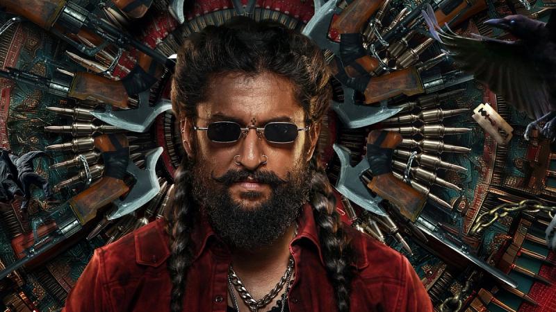 Nani as Jadal, in braids and dark glasses, in front of a wall of weapons in The Paradise