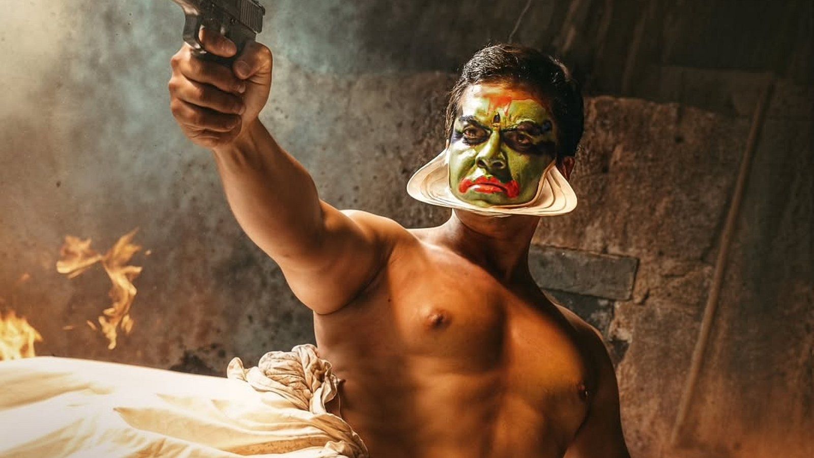 Indrajith in Kathakali face paint holding up a gun in the Nayakan re-release art