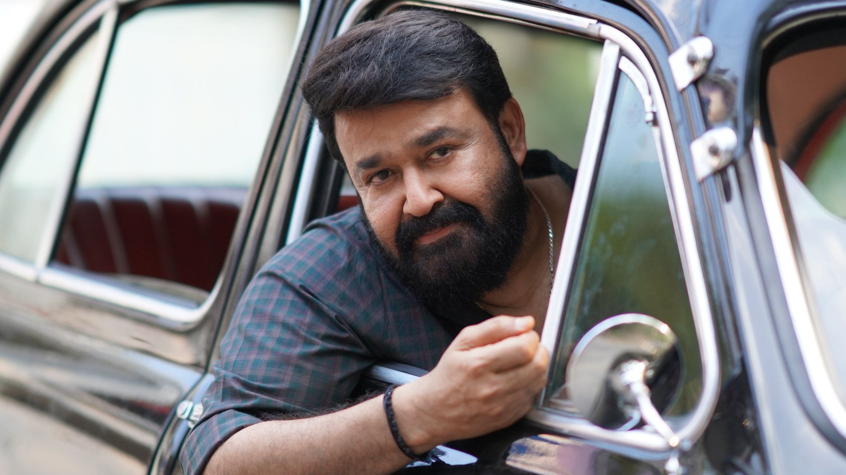 Thudarum still of Mohanlal leaning out of a car window, looking ahead