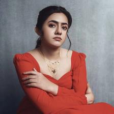 Femina George in a red dress seated against a grey backdrop