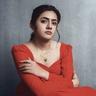 Femina George in a red dress seated against a grey backdrop