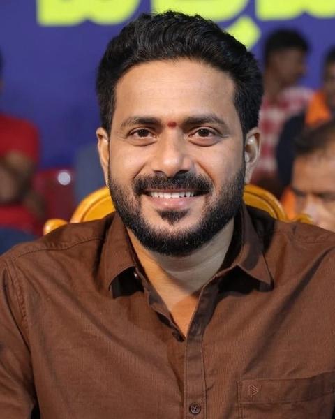 J. P. Thuminad smiling in a brown shirt at an indoor event