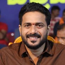 J. P. Thuminad smiling in a brown shirt at an indoor event