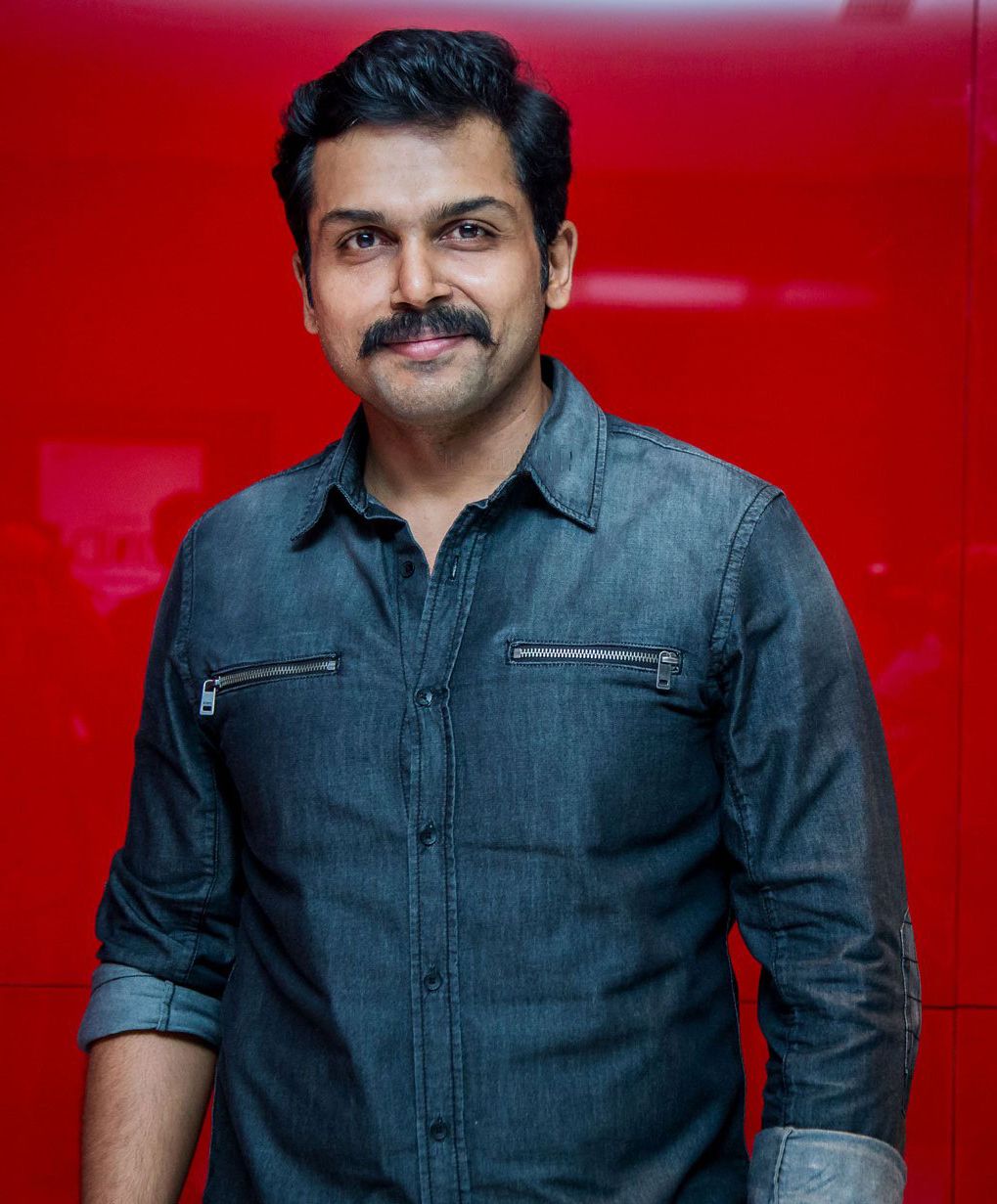 Karthi in a denim shirt against a red background