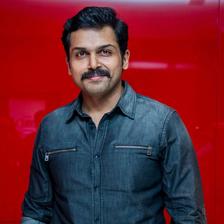Karthi in a denim shirt against a red background
