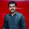Karthi in a denim shirt against a red background
