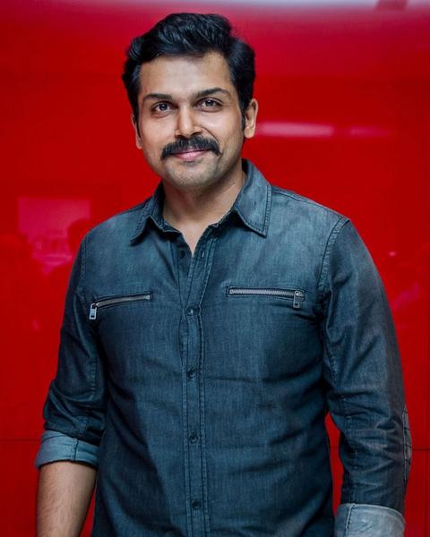 Karthi in a denim shirt against a red background