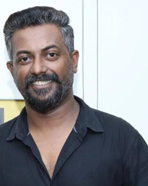 Binu Pappu in a black shirt against a light wall, portrait