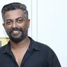 Binu Pappu in a black shirt against a light wall, portrait