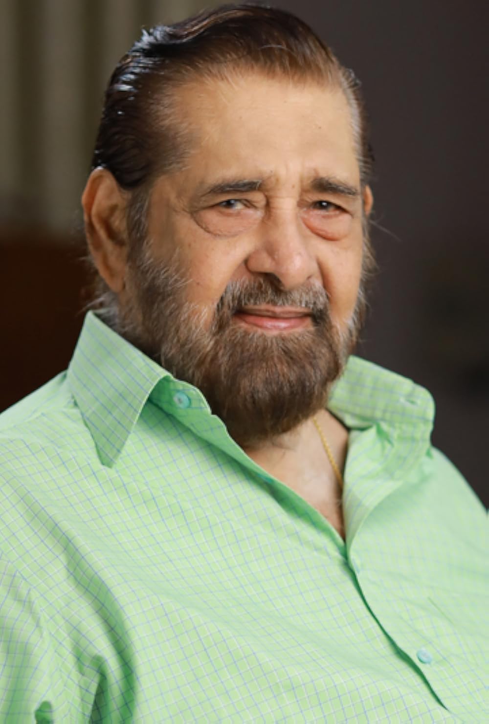 Madhu in a pale green checked shirt, smiling, half-length portrait
