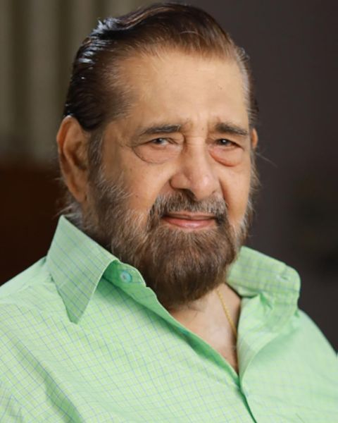 Madhu in a pale green checked shirt, smiling, half-length portrait