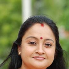 Geetha Vijayan smiling in an orange saree with a red bindi