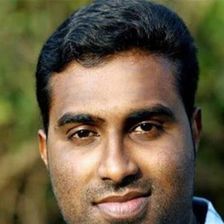 Jinu Abraham in a checked shirt outdoors, close-up portrait