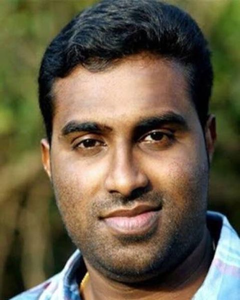 Jinu Abraham in a checked shirt outdoors, close-up portrait