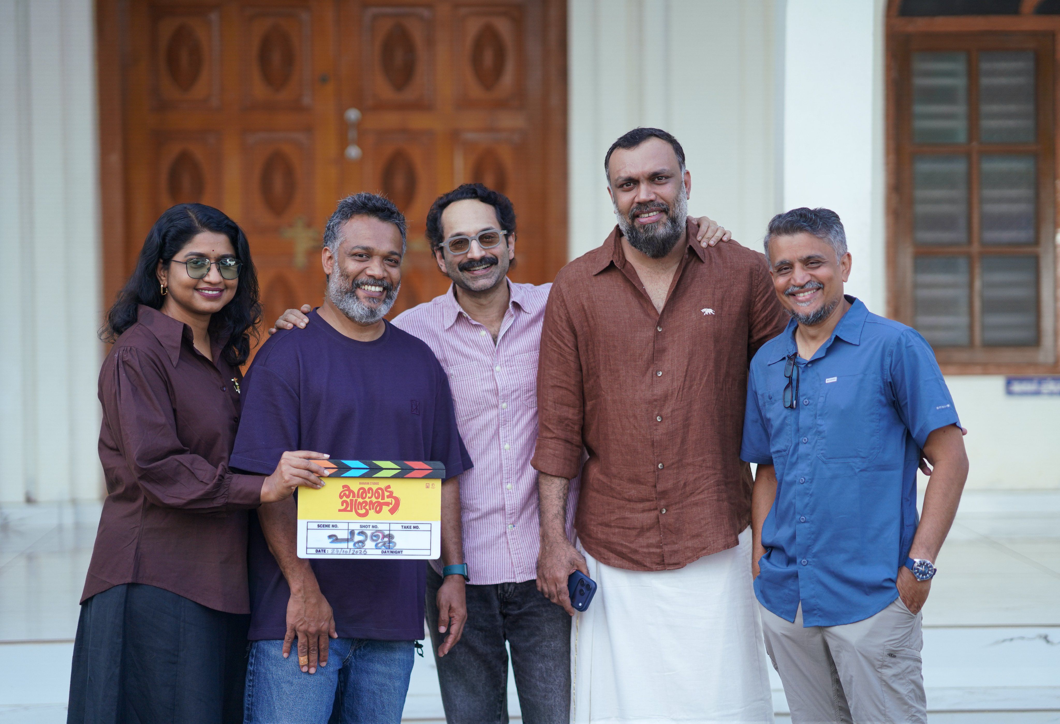 Fahadh Faasil holding the Karate Chandran clapboard with the team at the film's pooja