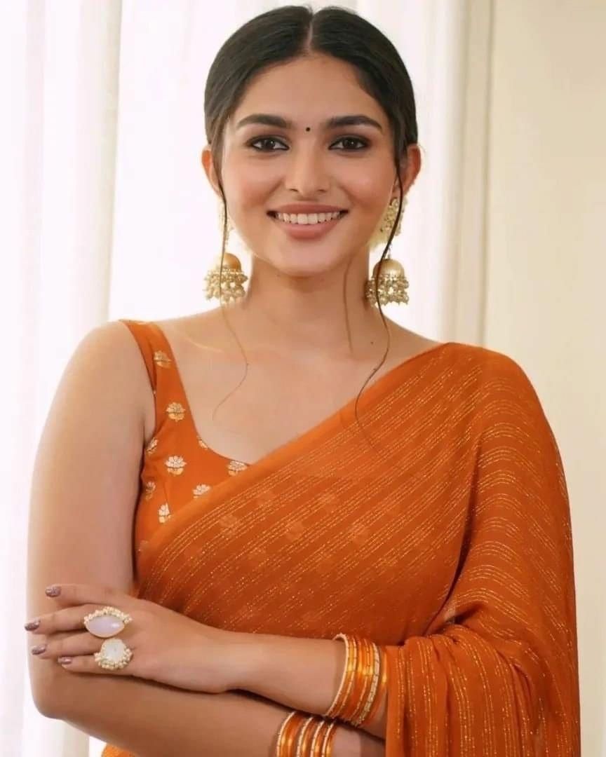 Kayadu Lohar in an orange saree, smiling, half-length portrait