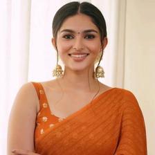 Kayadu Lohar in an orange saree, smiling, half-length portrait