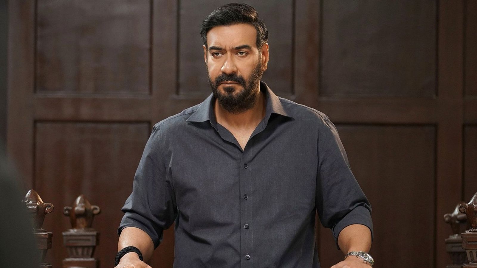 Ajay Devgn as Vijay Salgaonkar standing in a grey shirt in Drishyam: The Conclusion
