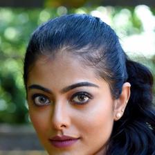 Merin Philip in a yellow high-neck top with her hair pulled back, green background portrait