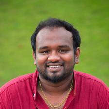 Vishnu Vijay smiling in a maroon shirt and gold chain against a green lawn, head-and-shoulders portrait