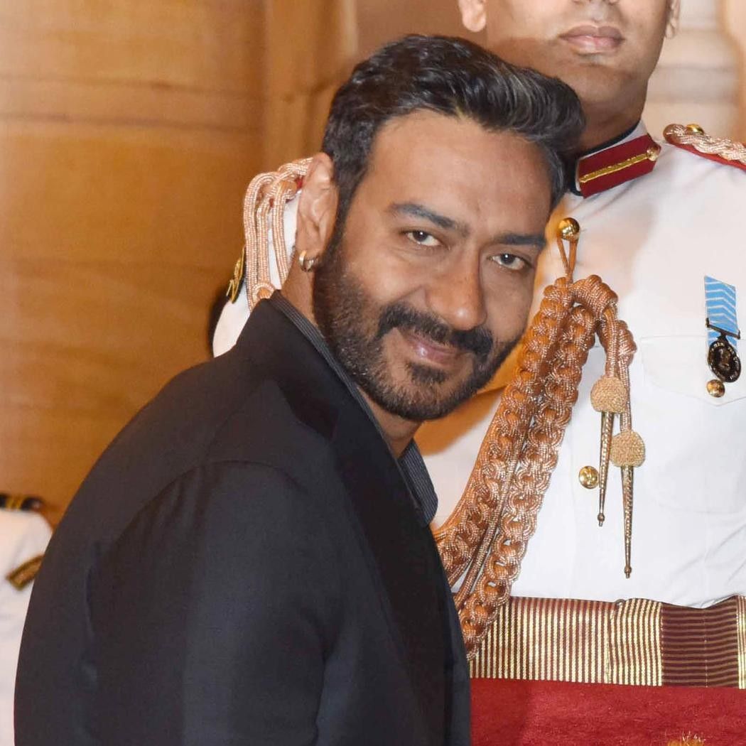 Ajay Devgn in a dark suit at a formal event with a ceremonial guard
