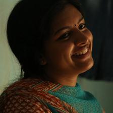 Lijomol Jose smiling in a dimly lit room, close-up portrait
