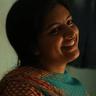 Lijomol Jose smiling in a dimly lit room, close-up portrait