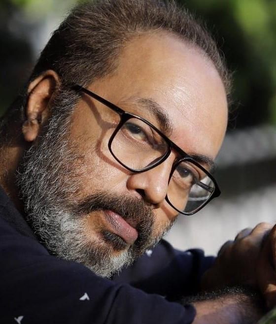 Shammi Thilakan in glasses with a grey beard, close-up portrait