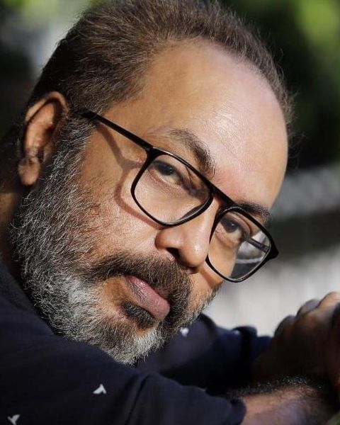 Shammi Thilakan in glasses with a grey beard, close-up portrait