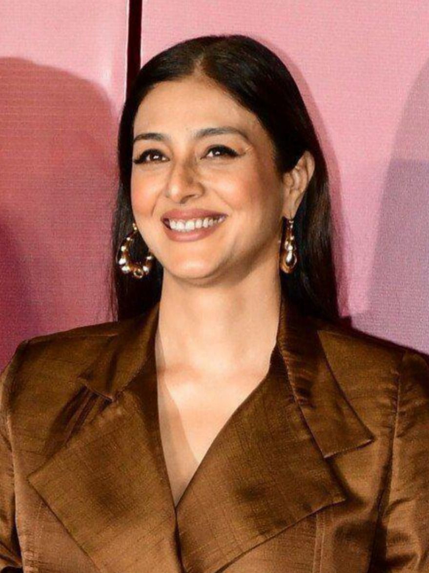 Tabu smiling in a brown blazer, close-up portrait