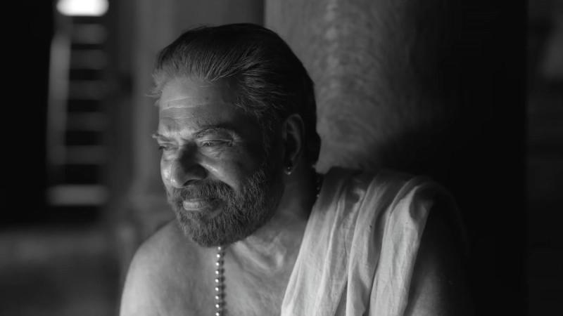 Mammootty smiling in a white mundu in a black-and-white frame from the Bramayugam trailer