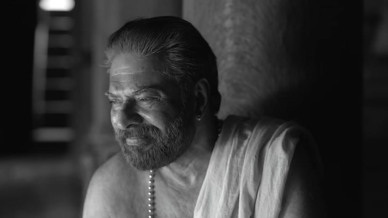 Mammootty smiling in a white mundu in a black-and-white frame from the Bramayugam trailer