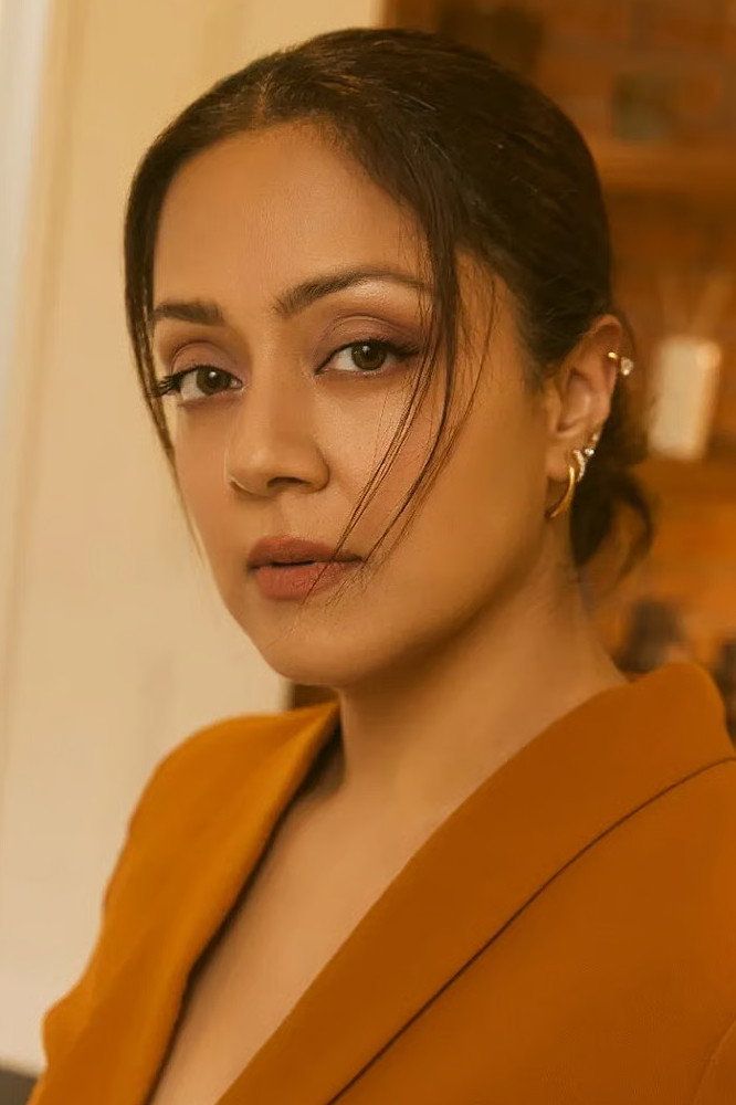 Jyothika in a mustard-yellow blazer with her hair tied back, looking at the camera