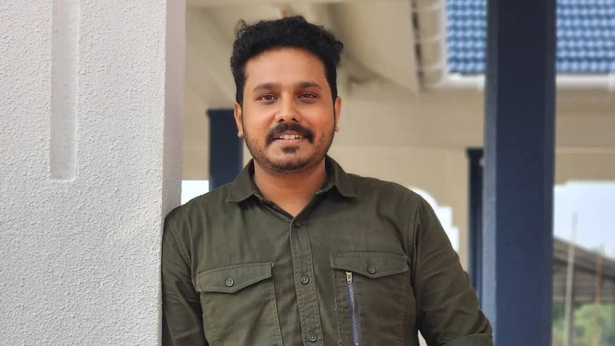Nahas Hidhayath in an olive shirt, smiling, leaning against a white pillar