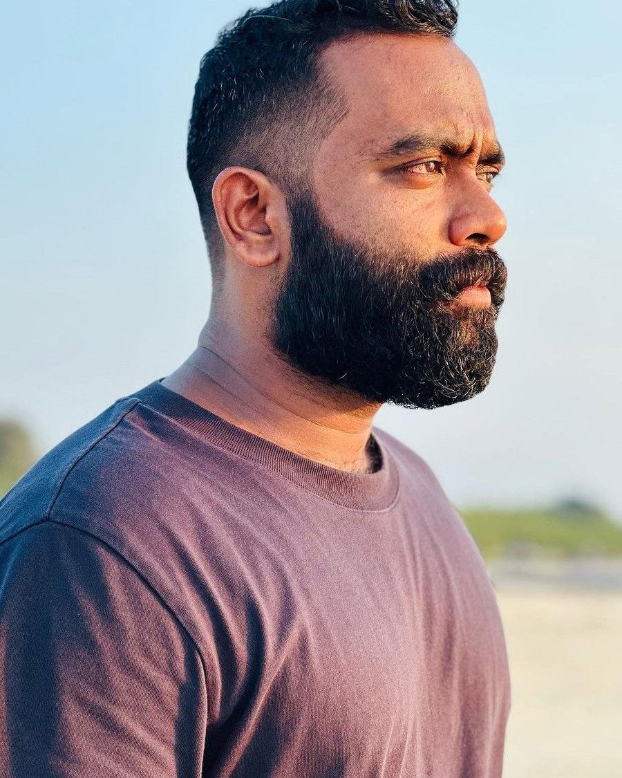 Sajin Gopu with a beard in a T-shirt, outdoor side profile