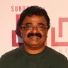 VTV Ganesh in rimless glasses and a dark green sweater at an event backdrop