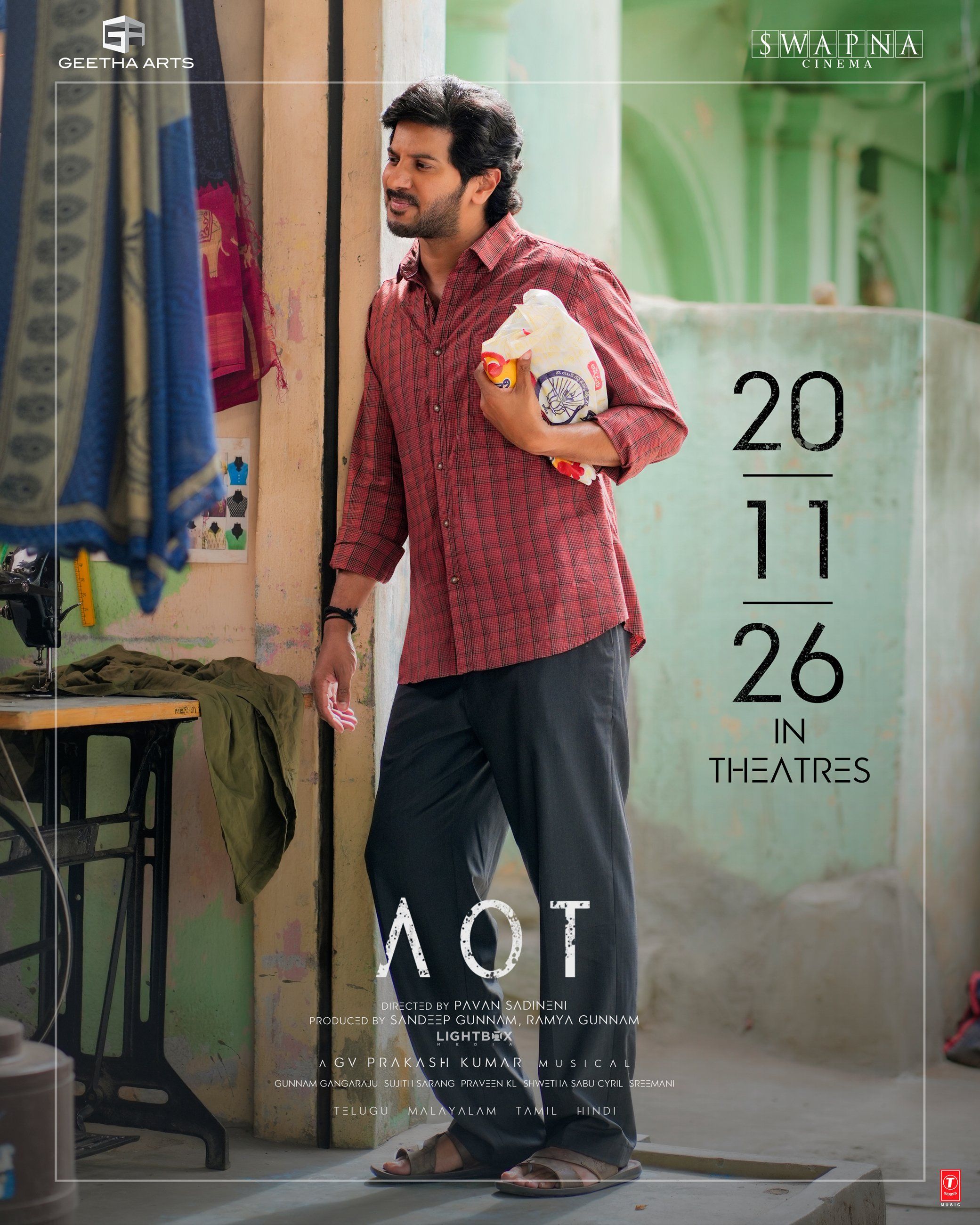 Aakasamlo Oka Tara poster showing Dulquer Salmaan in a red checked shirt beside a tailoring shop, with the 20.11.26 release date