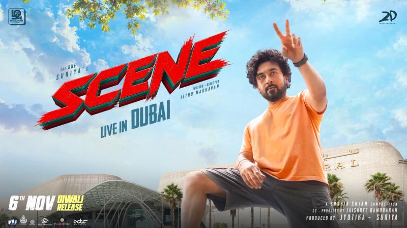 Suriya in an orange T-shirt flashing a victory sign on the Scene Live in Dubai poster with the November 6 Diwali release date