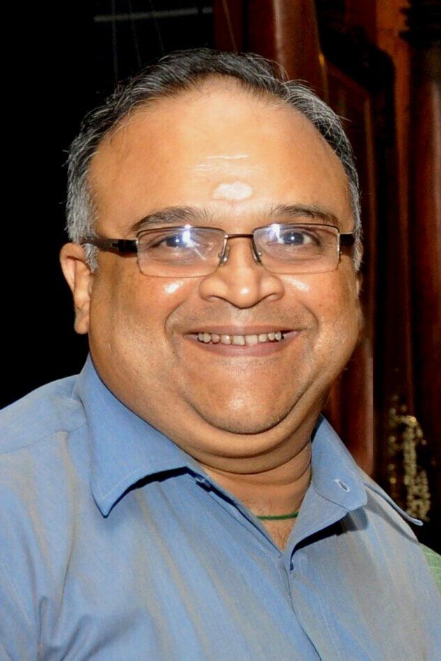 Mohan Raman smiling in glasses and a blue shirt, portrait