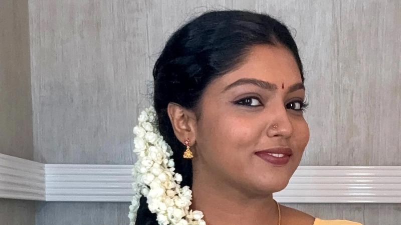 Chaithra Praveen smiling in a cream saree with jasmine in her hair